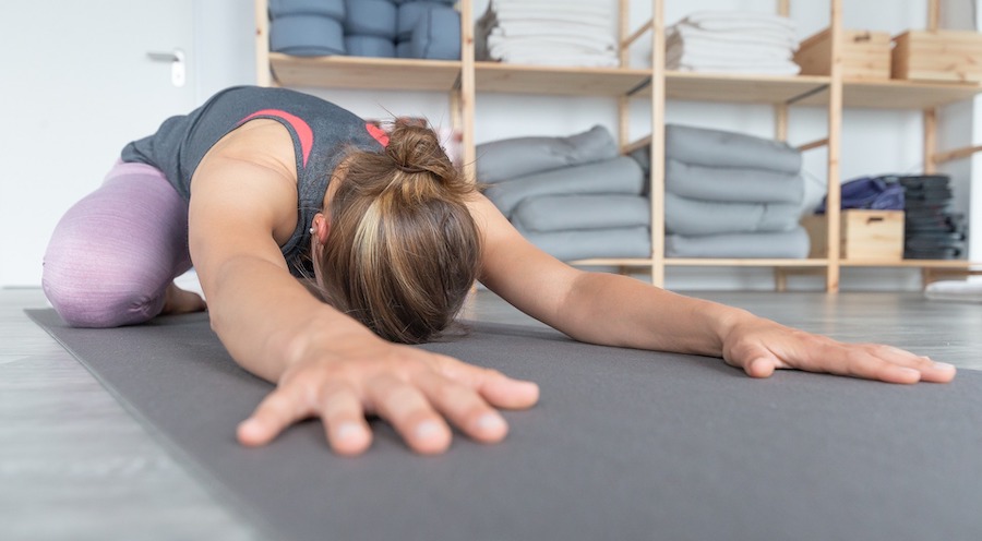 Young woman in wide knee child's pose in yoga studio